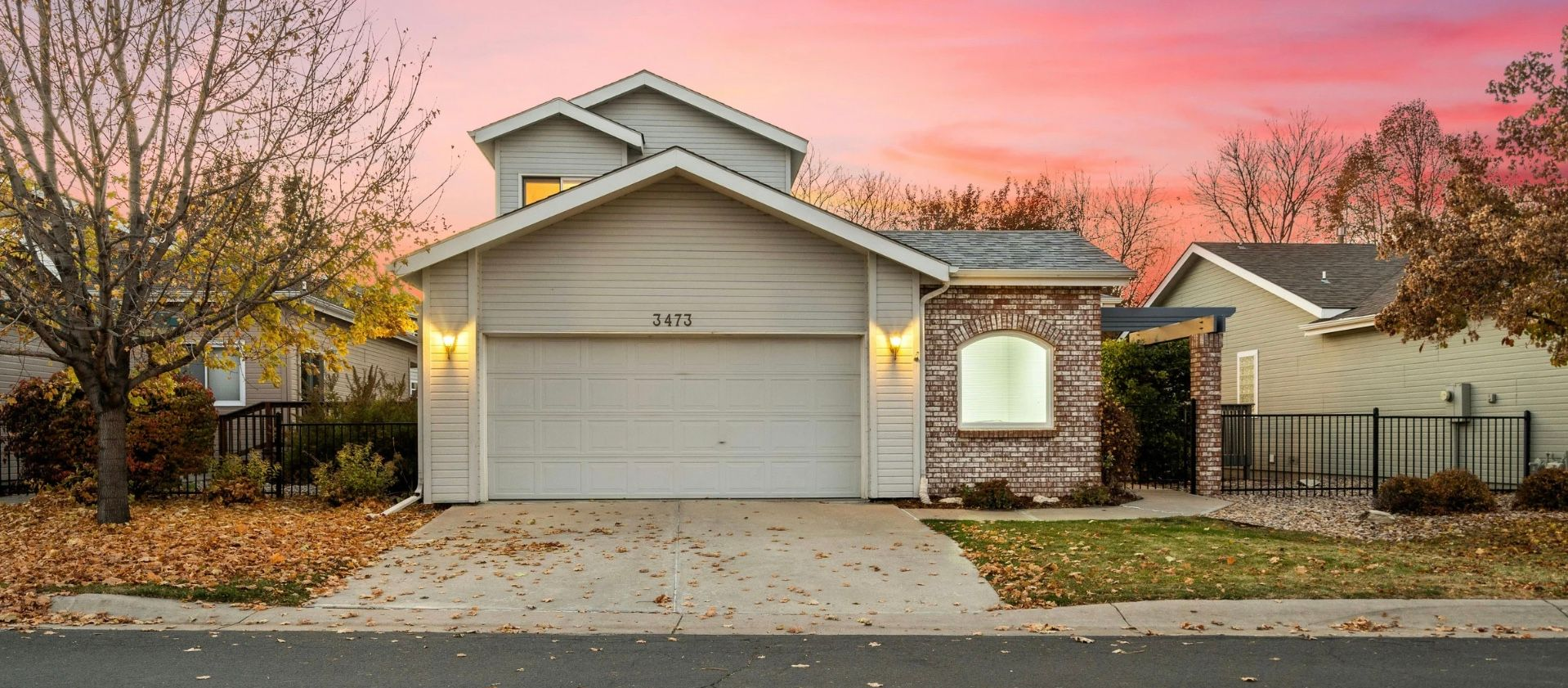 House with blue and white exterior, green lawn, trees, and bright blue sky.