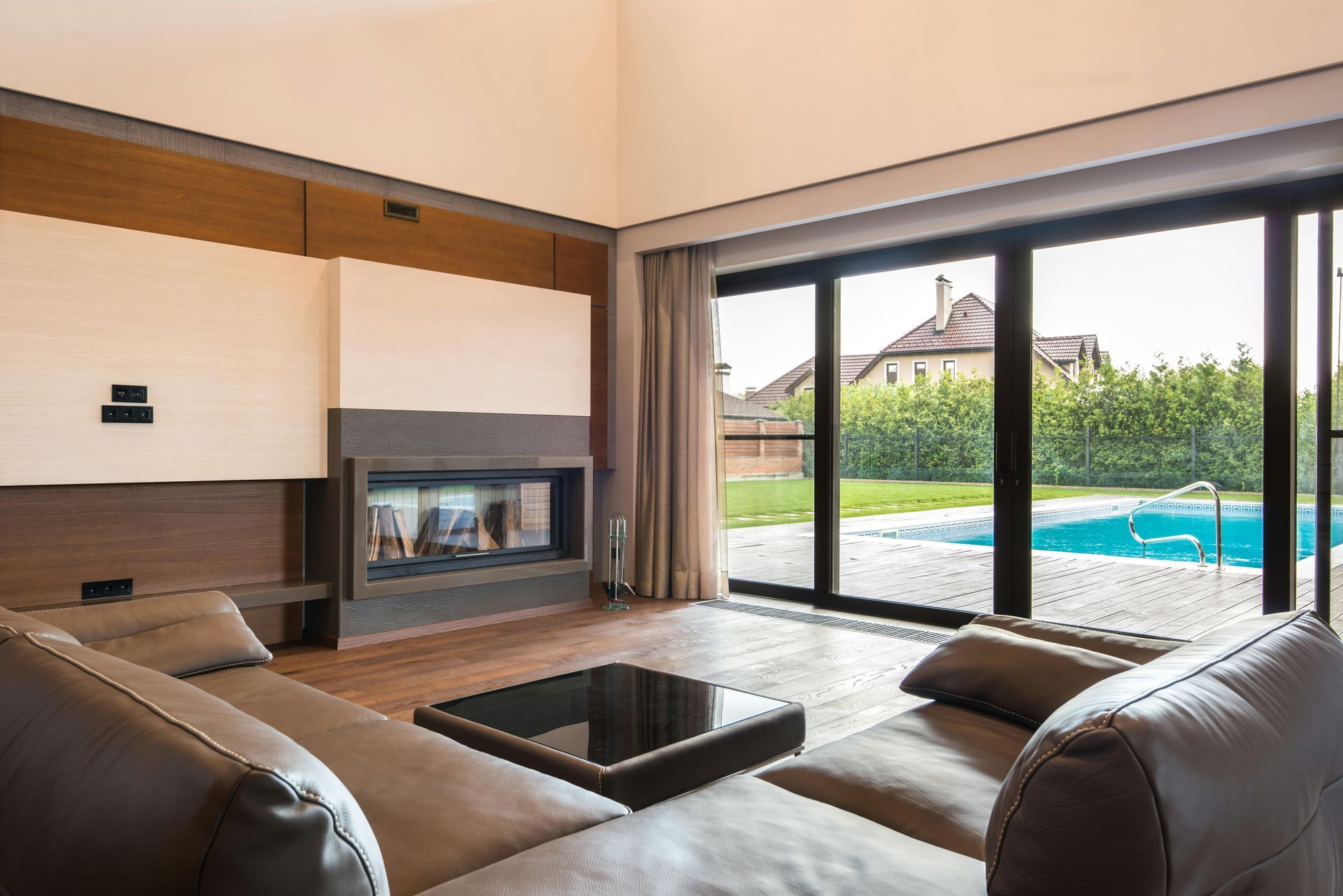 A living room with a couch , fireplace and sliding glass doors leading to a pool.