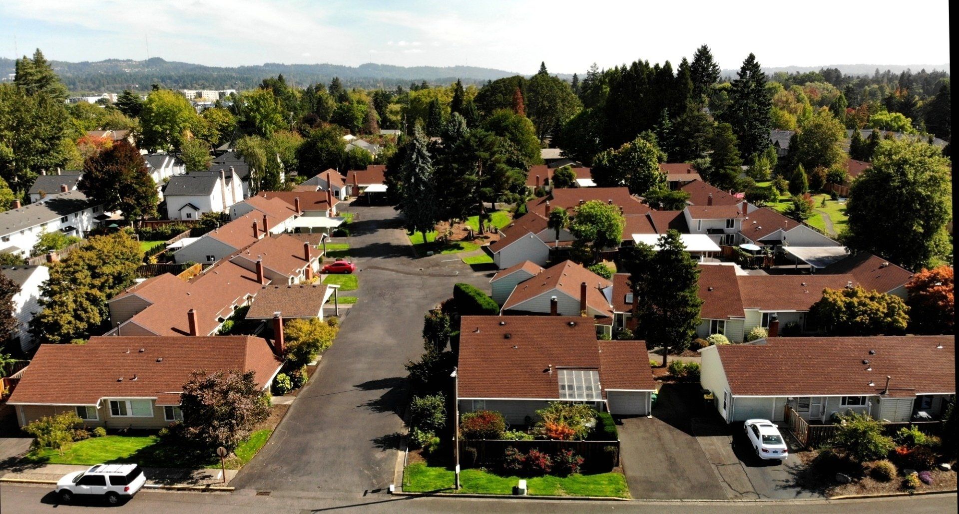 An aerial view of a residential neighborhood with cars parked on the side of the road