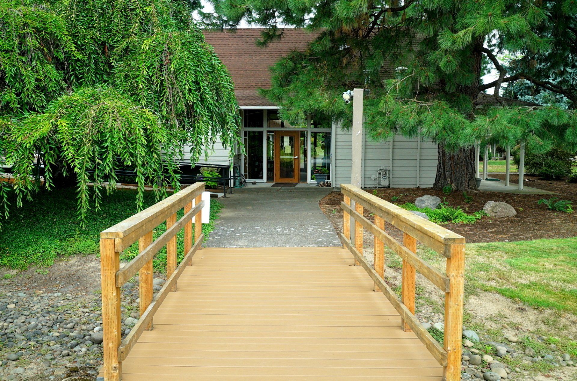 A wooden bridge leading to a building with trees in the background.
