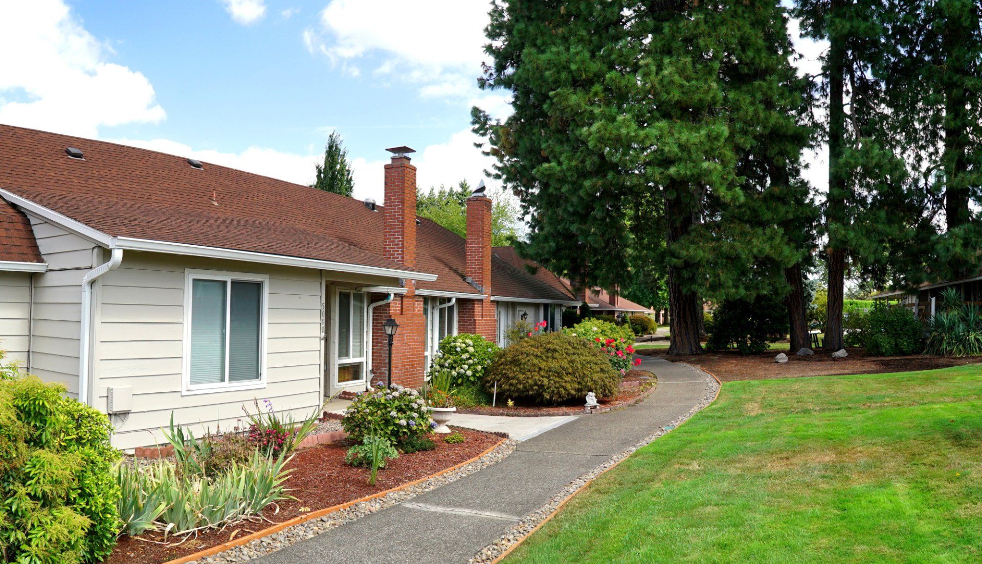 A white house with a brown roof and a walkway leading to it
