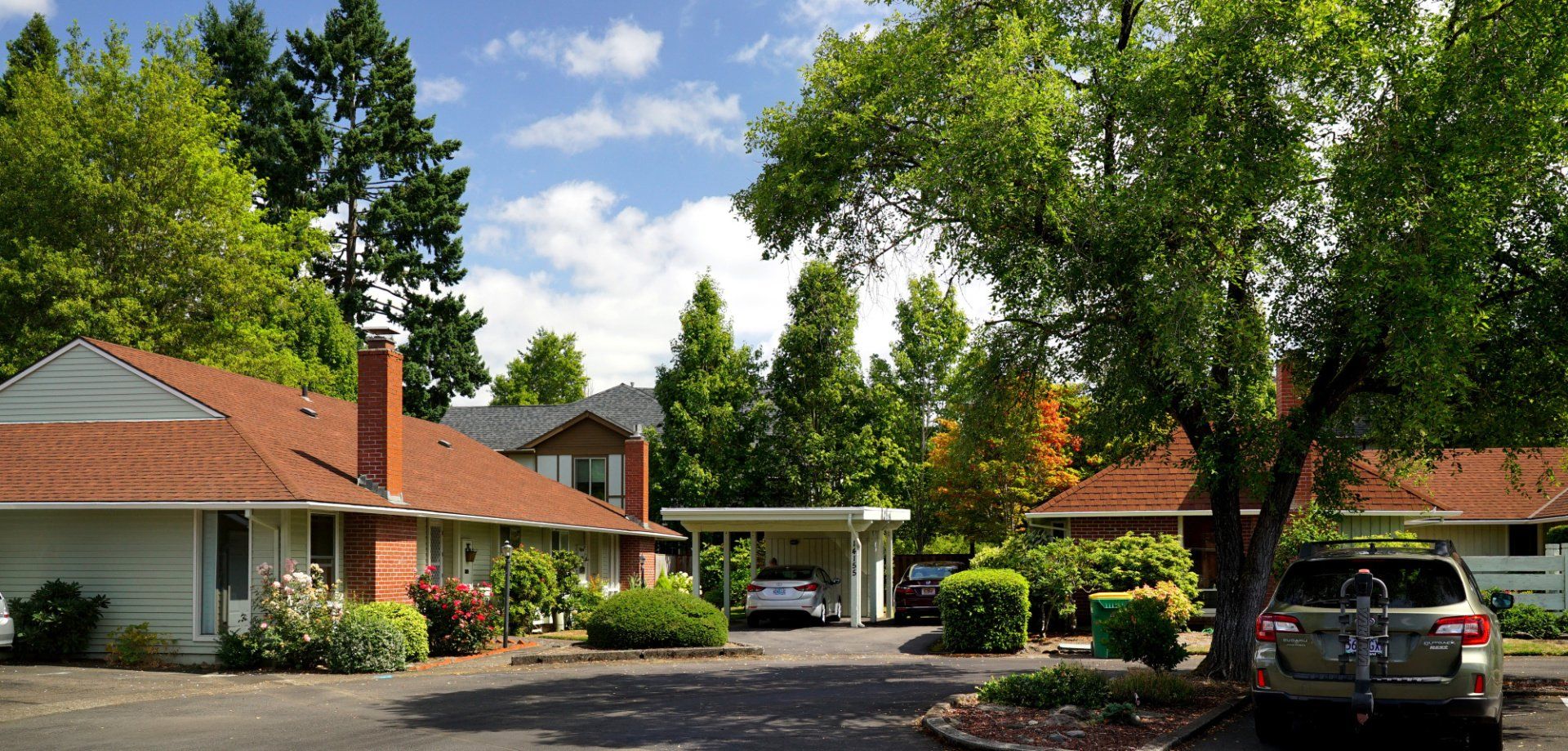 A row of houses with cars parked in front of them.