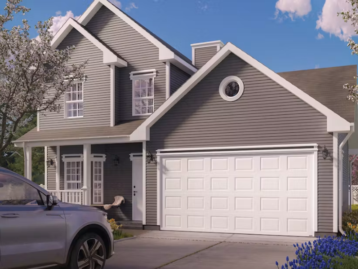 Row of suburban townhouses with lit windows and white garage doors at dusk