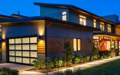 Modern two-story house at dusk with lit windows, garage, and landscaped front walkway
