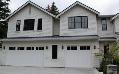 Two-story white townhouse with three white garage doors and black-trim windows