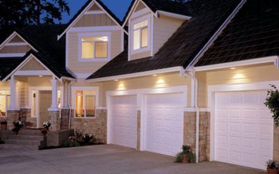 Row of suburban townhouses with lit windows and white garage doors at dusk