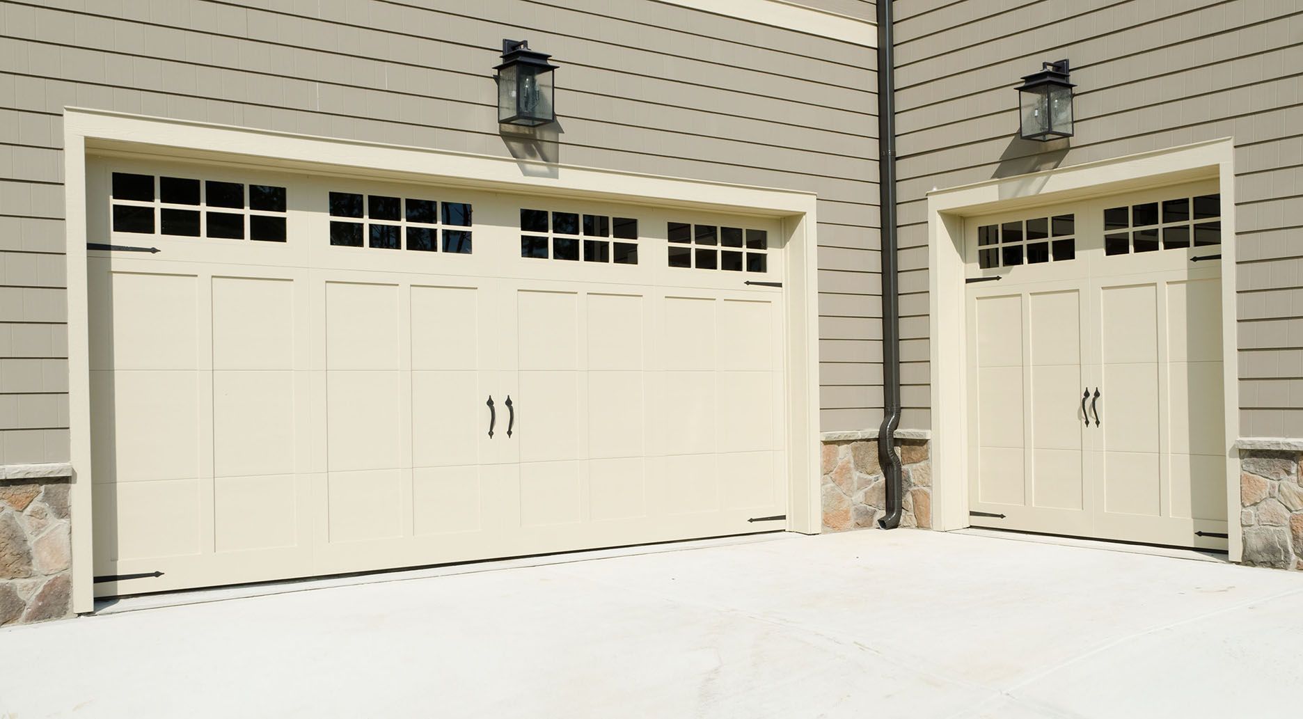 Snow-covered driveway with beige garage doors on a house exterior