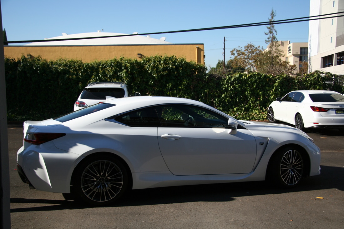 A white sports car is parked in a parking lot