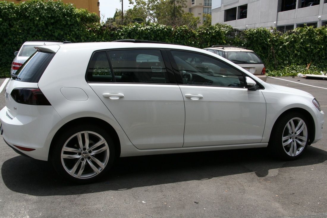 A white volkswagen golf is parked in a parking lot.