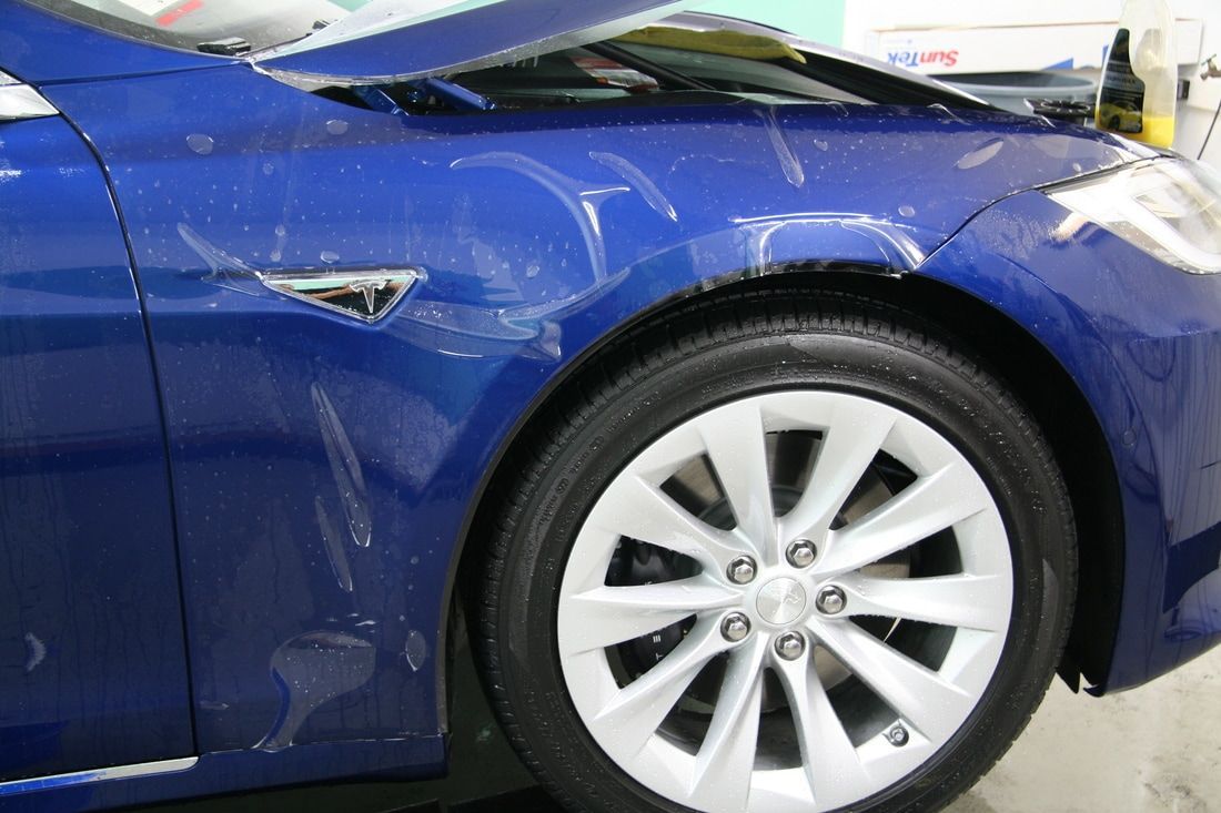 A blue tesla model s is parked in a garage.