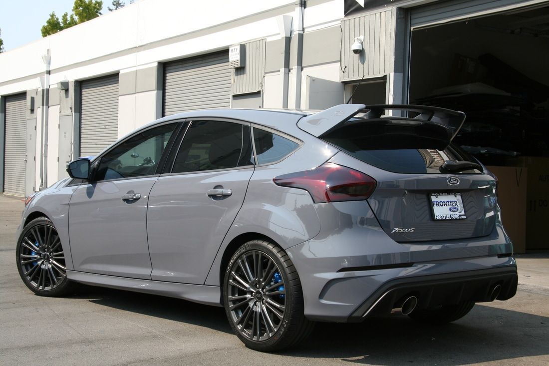 A gray ford focus rs is parked in front of a garage.