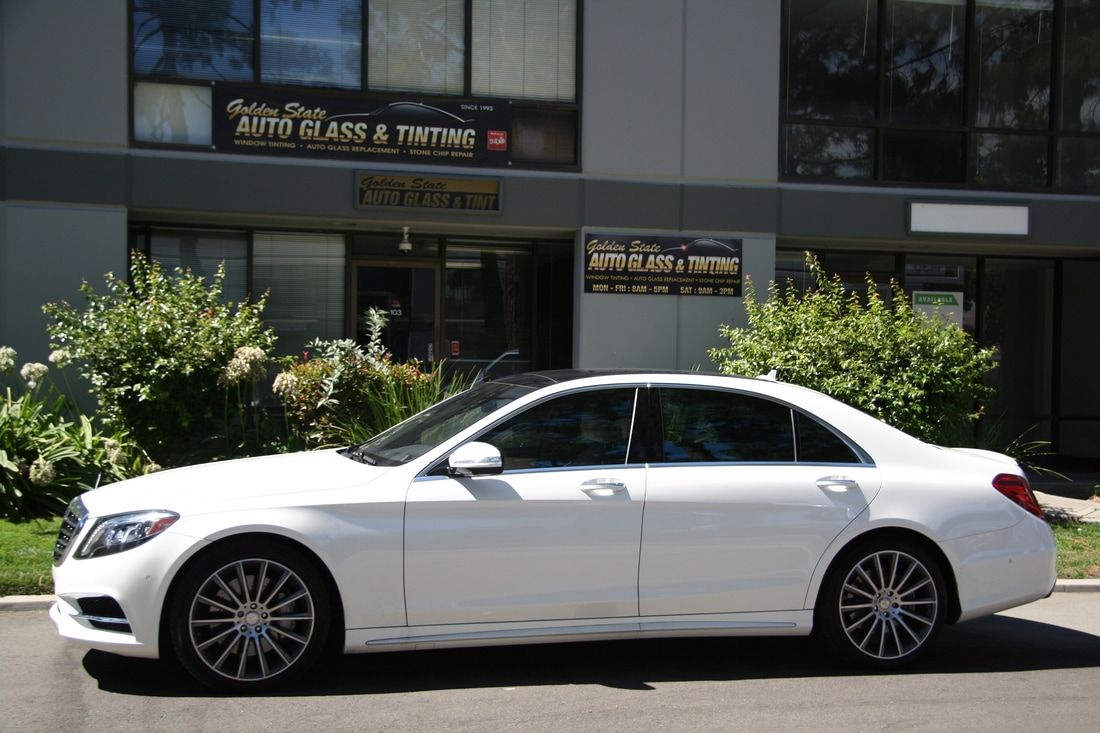 A white mercedes benz is parked in front of a building.