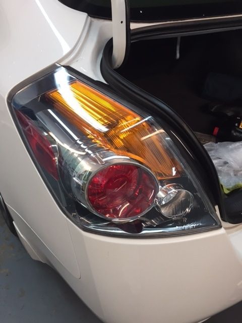 A close up of a car 's tail light with the trunk open