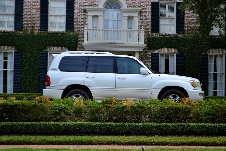 A white suv is parked in front of a brick house