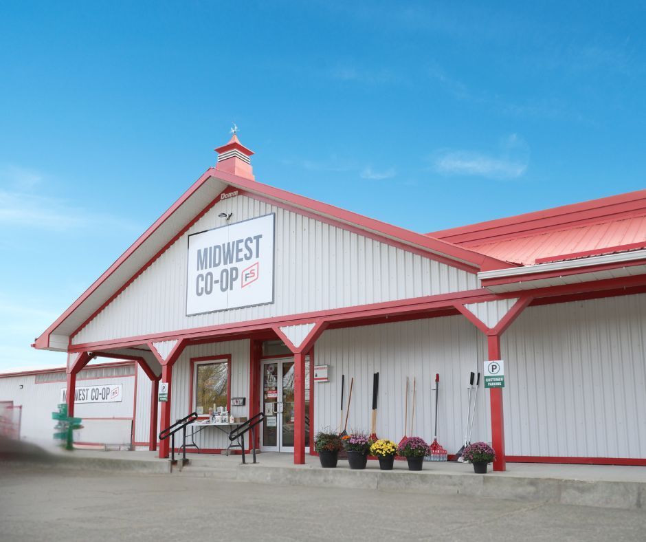 A row of lawn mowers are parked in front of a midwest co-op store.