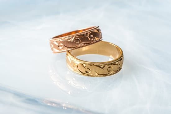 Two gold wedding rings are sitting on top of each other on a white surface.