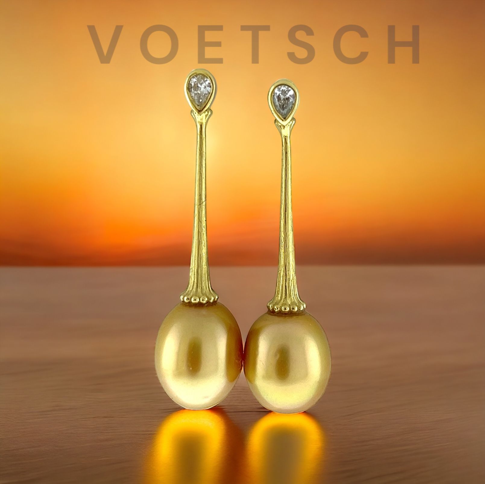 A pair of gold earrings with the word voetsch on the bottom