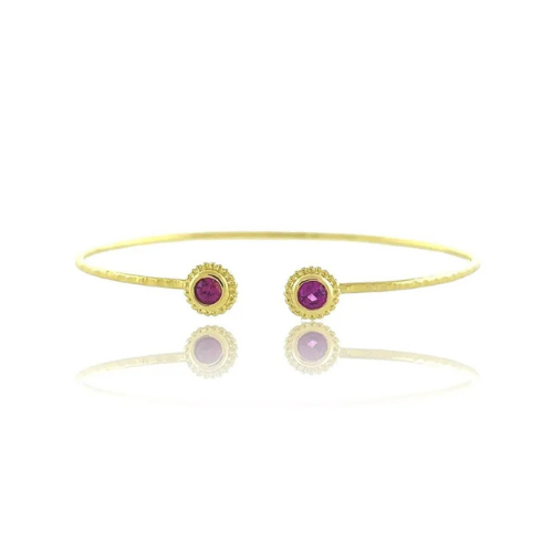 A gold bangle with two purple stones on a white background.