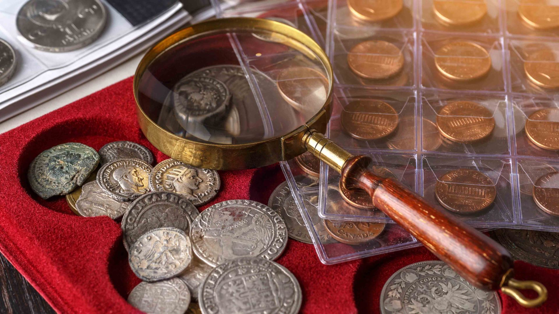 Coin collection supplies with antique coins, magnifier, and storage cases for collectors and dealers.