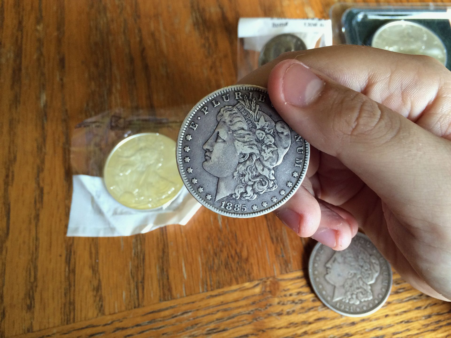 A hand holds an American silver dollar with coin supplies from Treasure Island Stamps and Coins in S