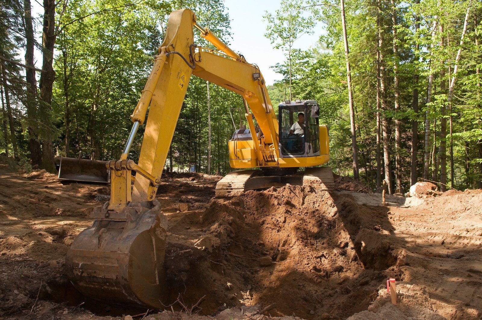 A yellow excavator is sitting on top of a pile of gravel.