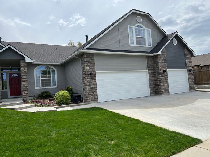 A large house with two garage doors and a large lawn in front of it.