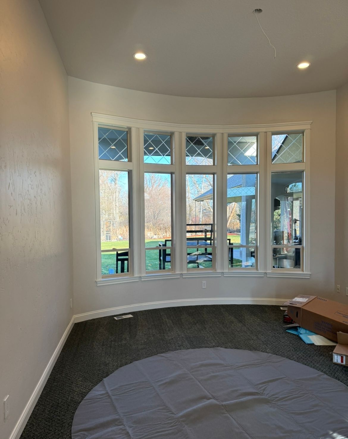 A living room with a lot of windows and a round rug on the floor.