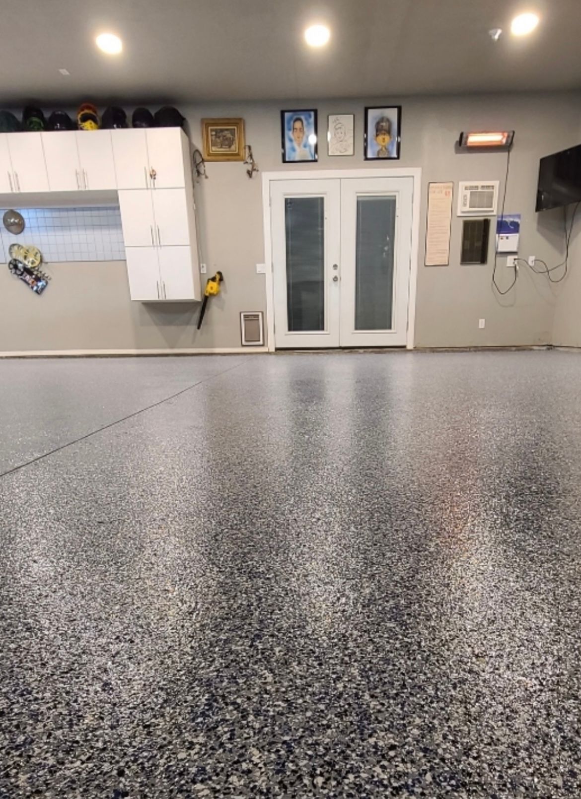 A garage with a gray floor and white cabinets.