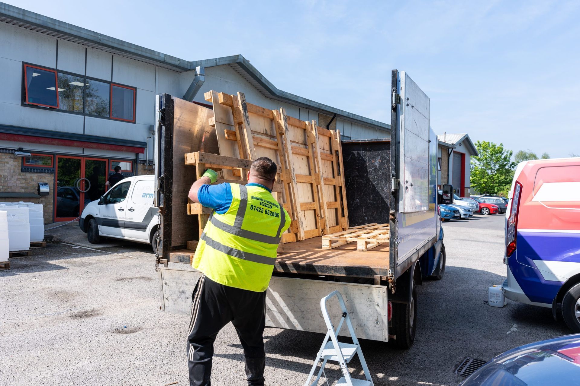 man loading empty pallets into the back of a rf recycling van 