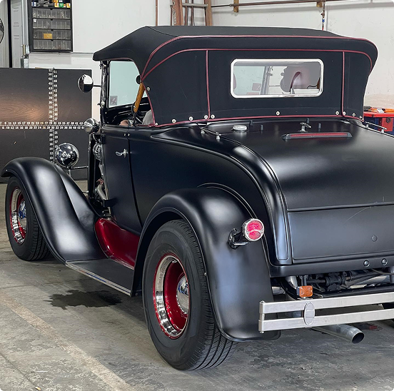 Black convertible car with red accents in a garage. | Las Truck & Auto