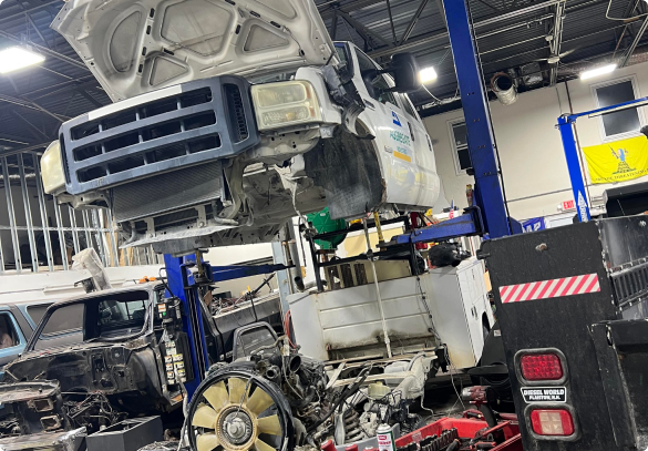 A truck cab suspended in a repair shop, its hood open. The engine is exposed. | Las Truck Auto