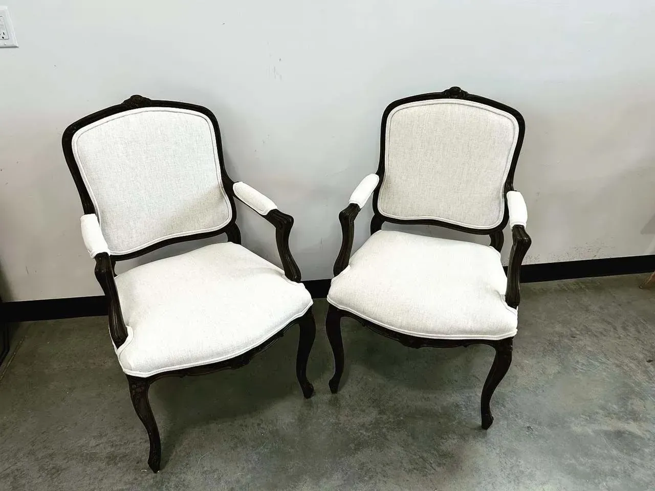 Two white chairs are sitting next to each other in a room.