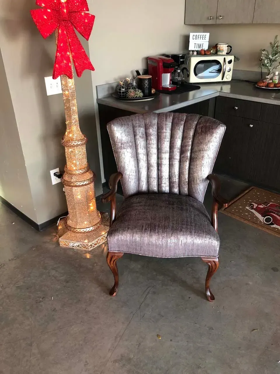 A chair is sitting next to a christmas tree in a kitchen.
