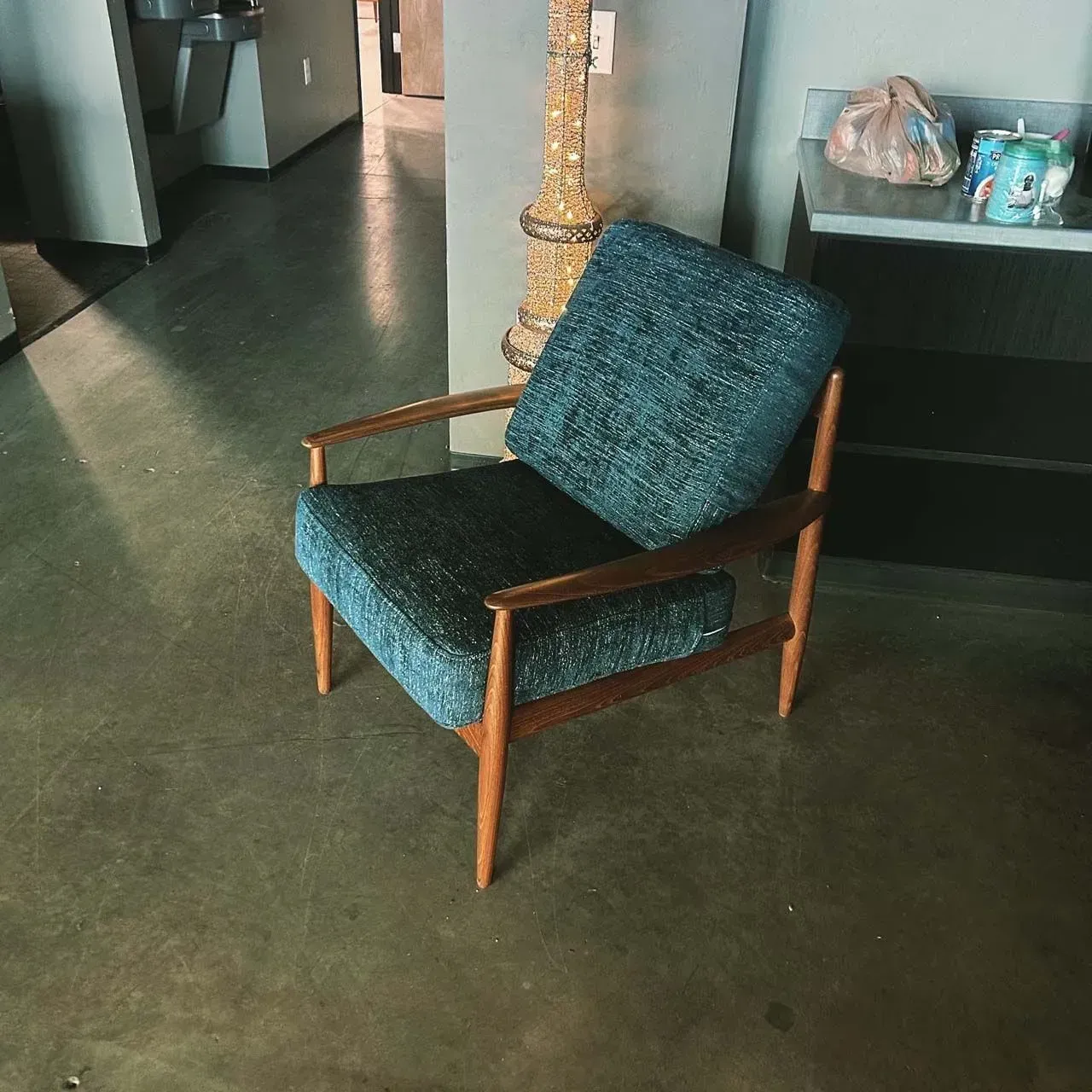 A chair with a blue cushion and wooden arm rests