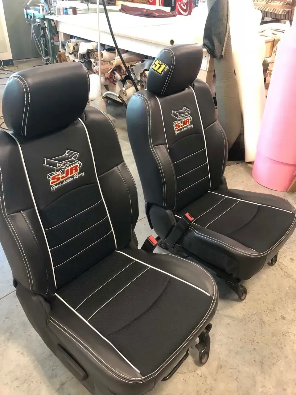 A pair of black leather seat covers are sitting on a concrete floor.