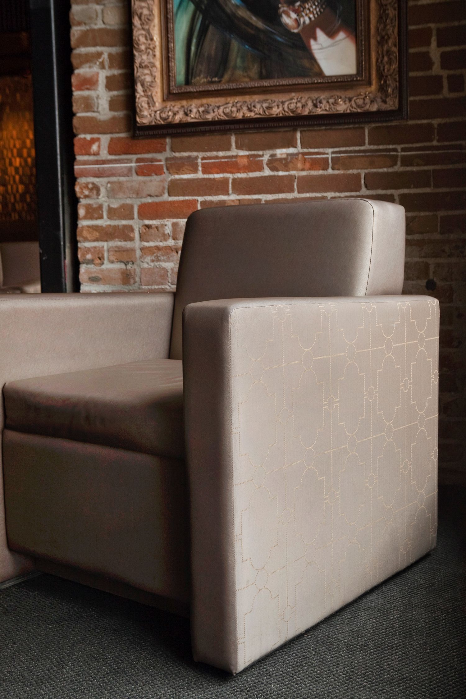 A chair is sitting in front of a brick wall with a painting on it.