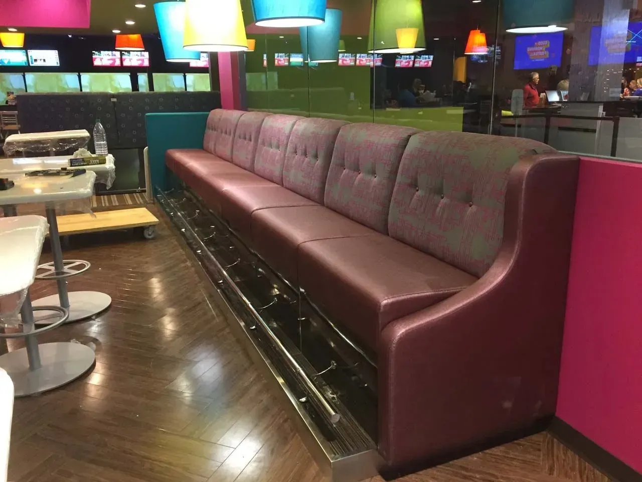 A long couch in a restaurant with tables and chairs