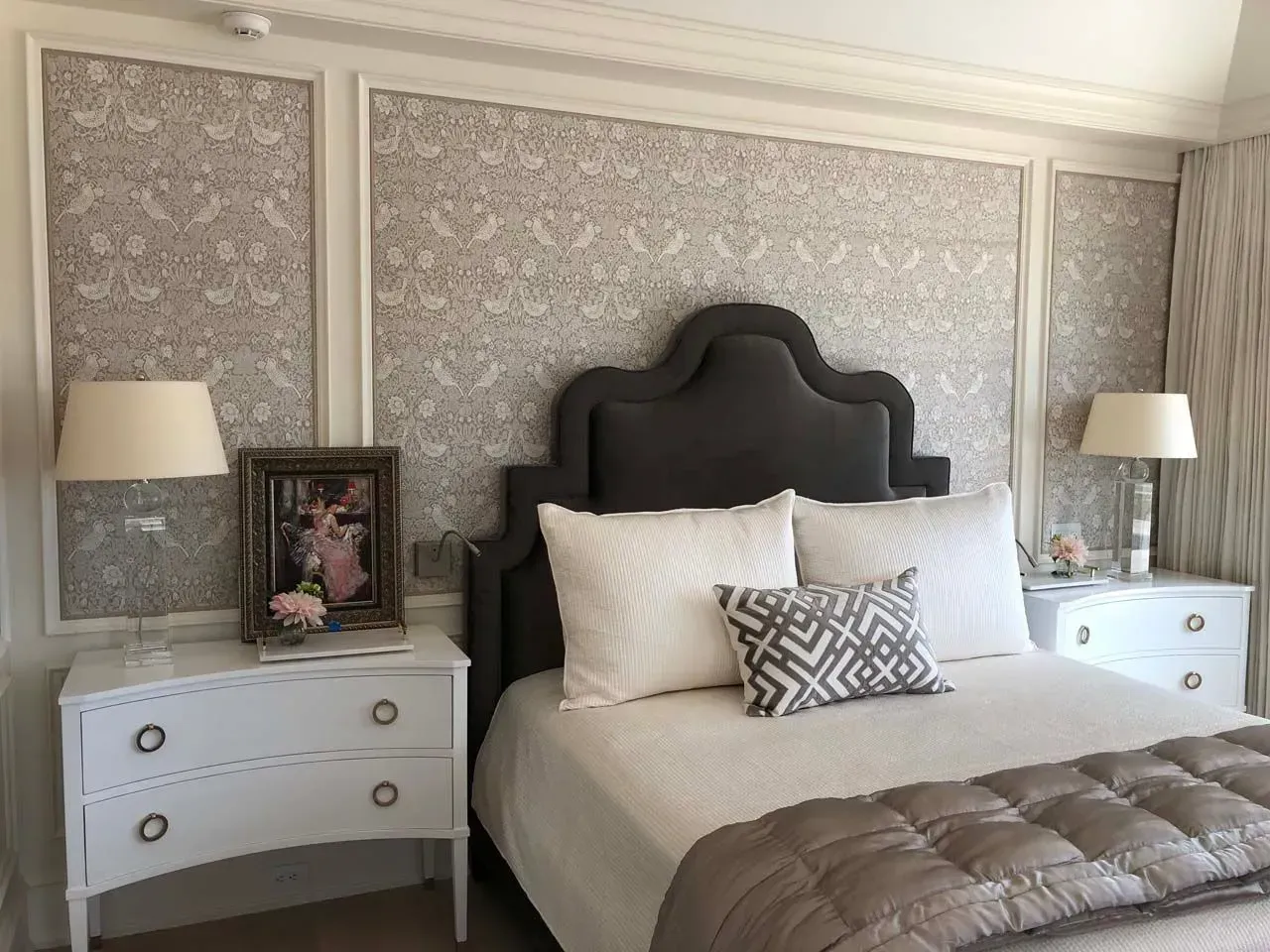 A bedroom with a bed , nightstands , lamps and a picture on the wall.