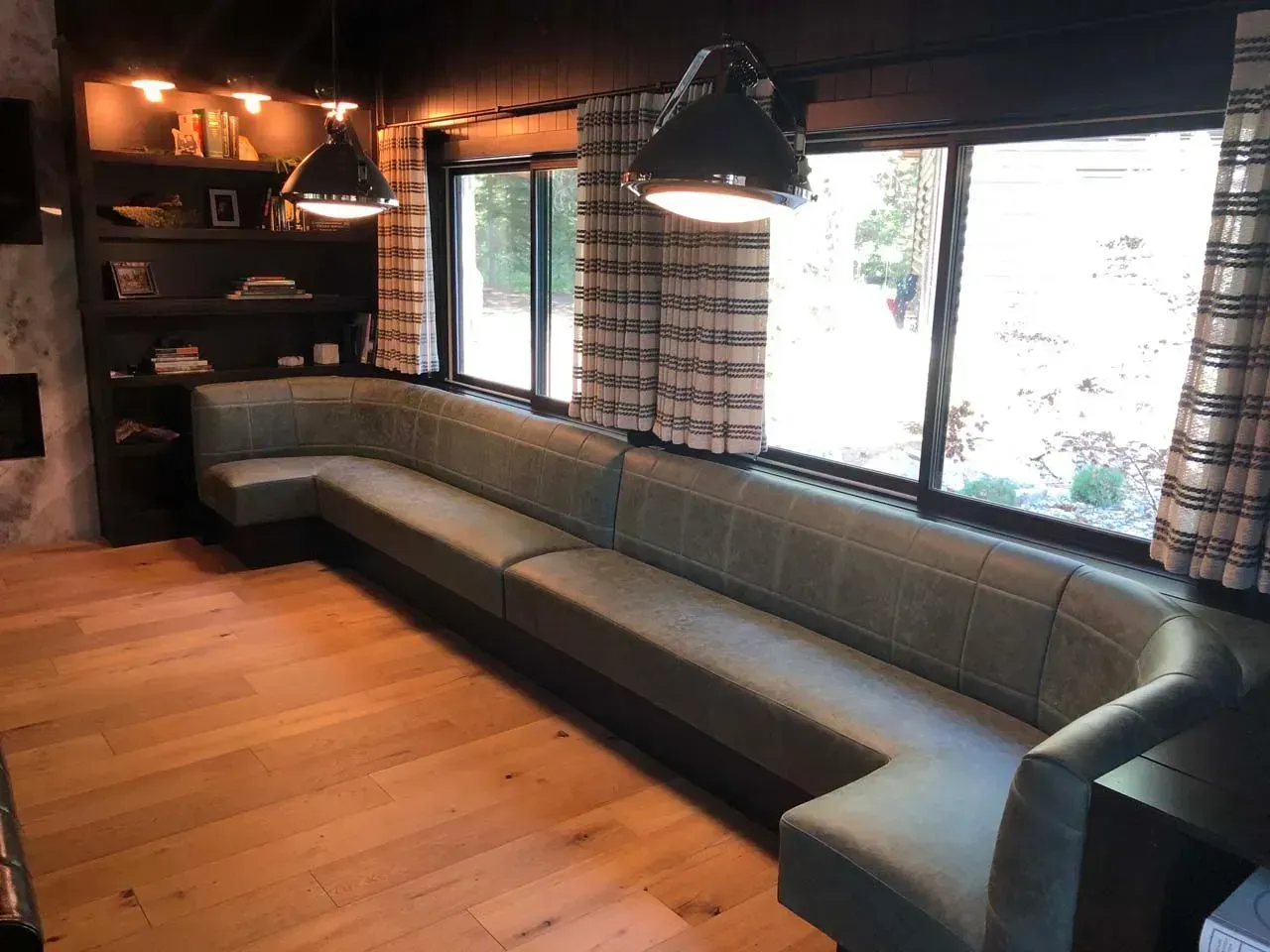 A long couch is sitting in a living room next to a window.