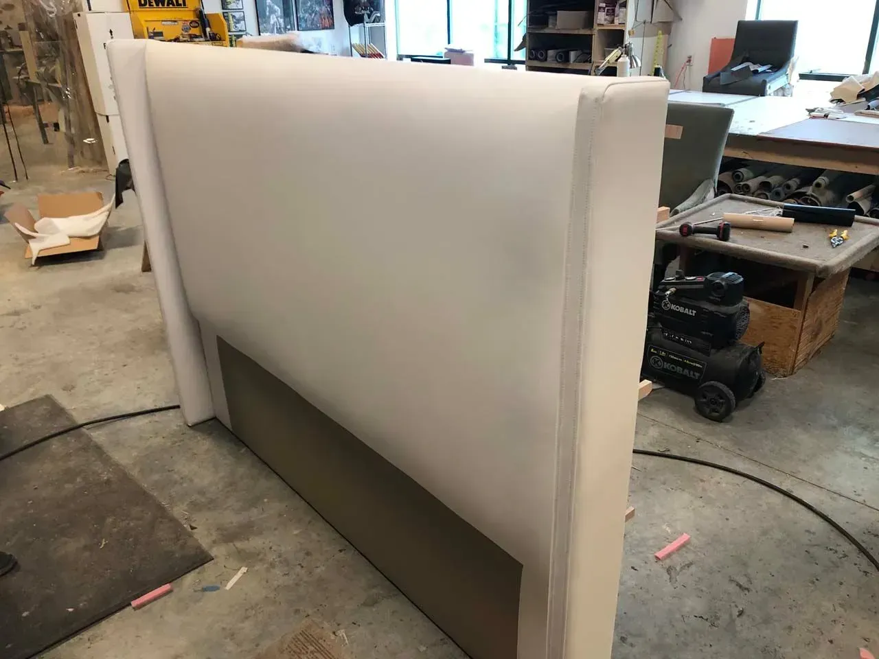 A white headboard is sitting on the floor in a room.