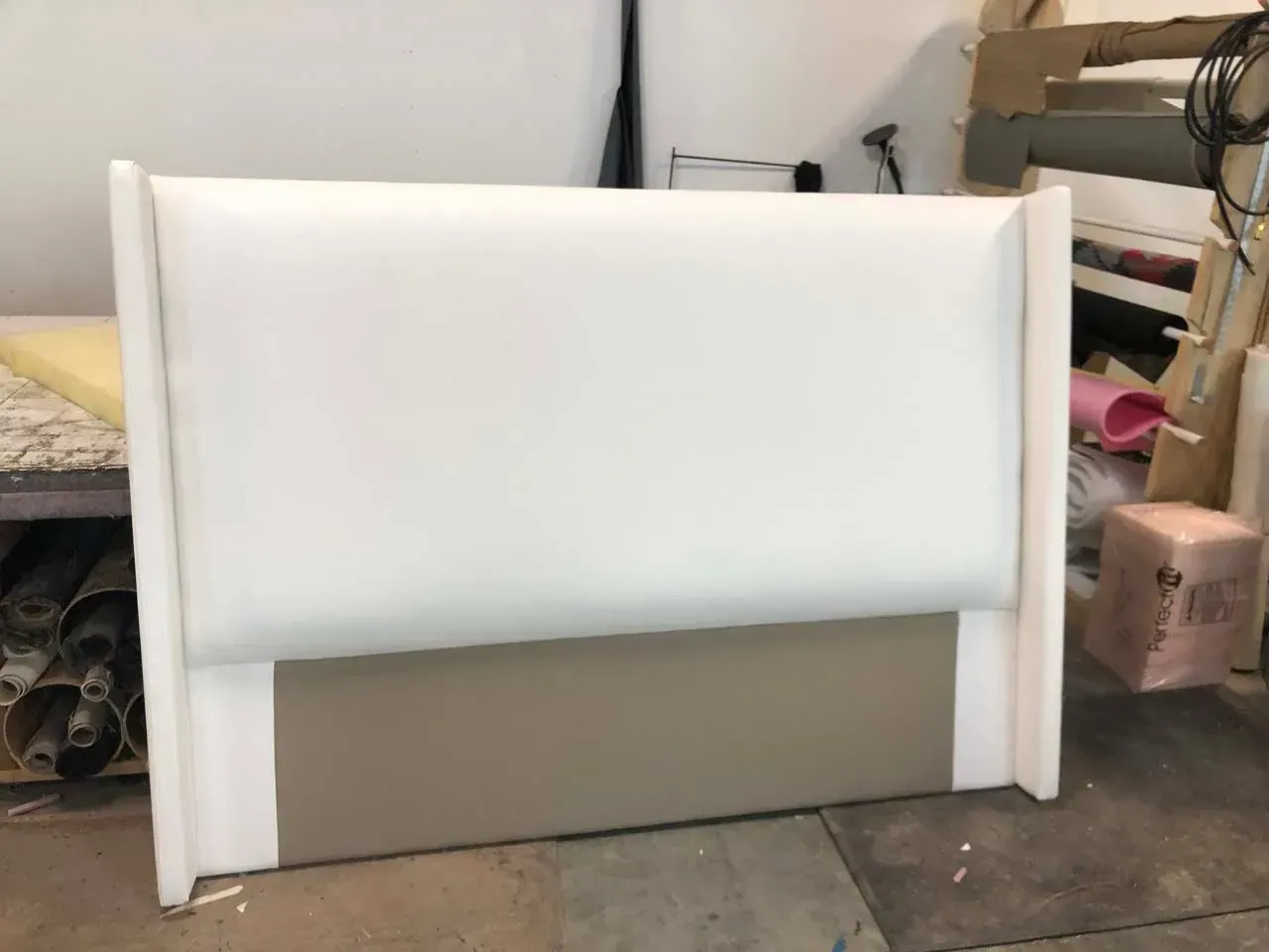 A white headboard is sitting on a table in a room.