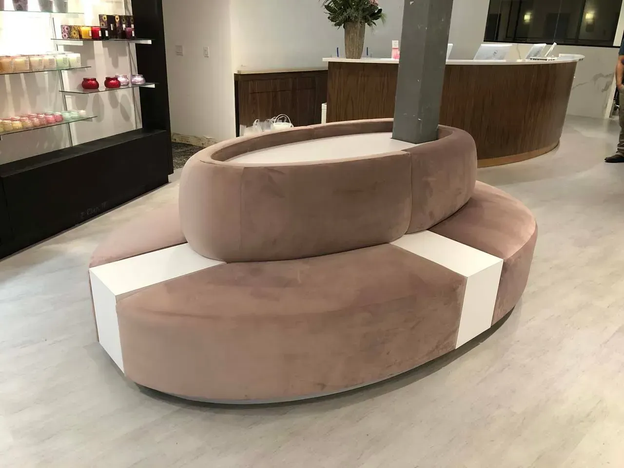 A round couch is sitting in a room next to a counter.
