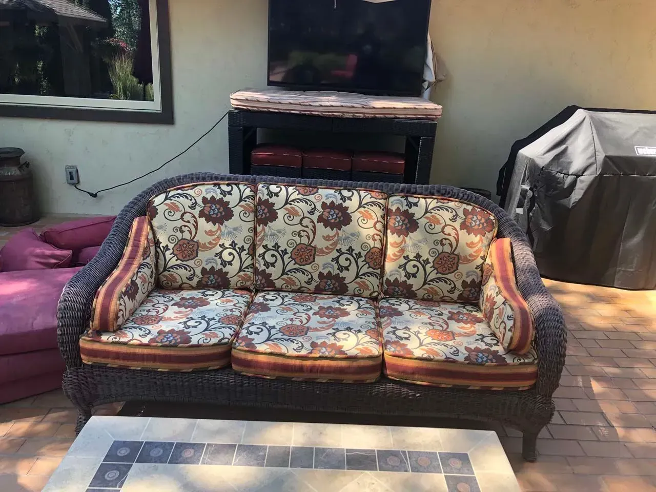 A wicker couch with a floral pattern sits on a patio