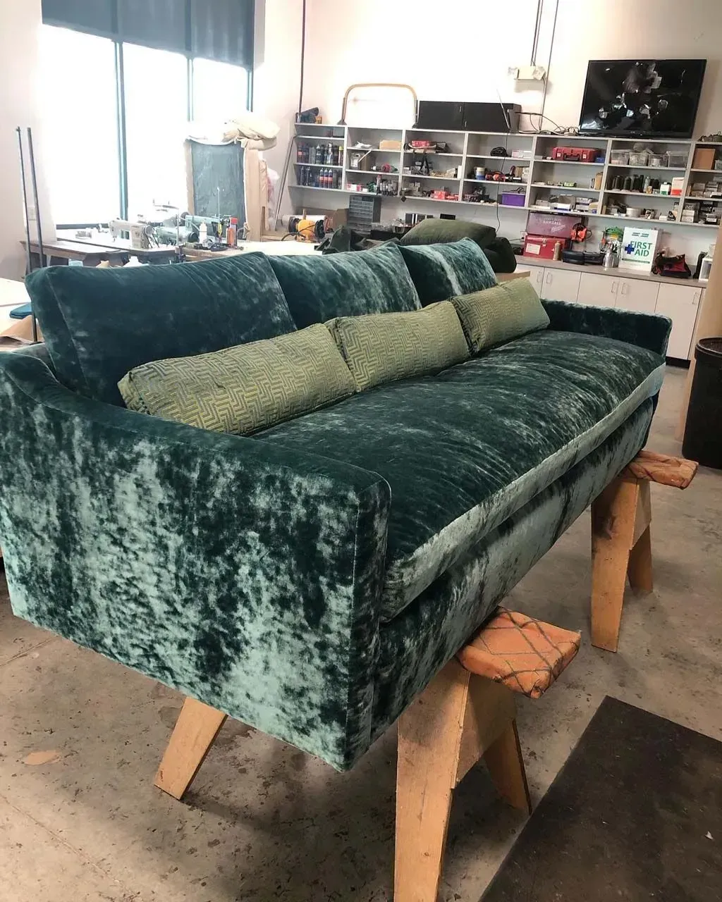 A green couch is sitting on a wooden stool in a room.