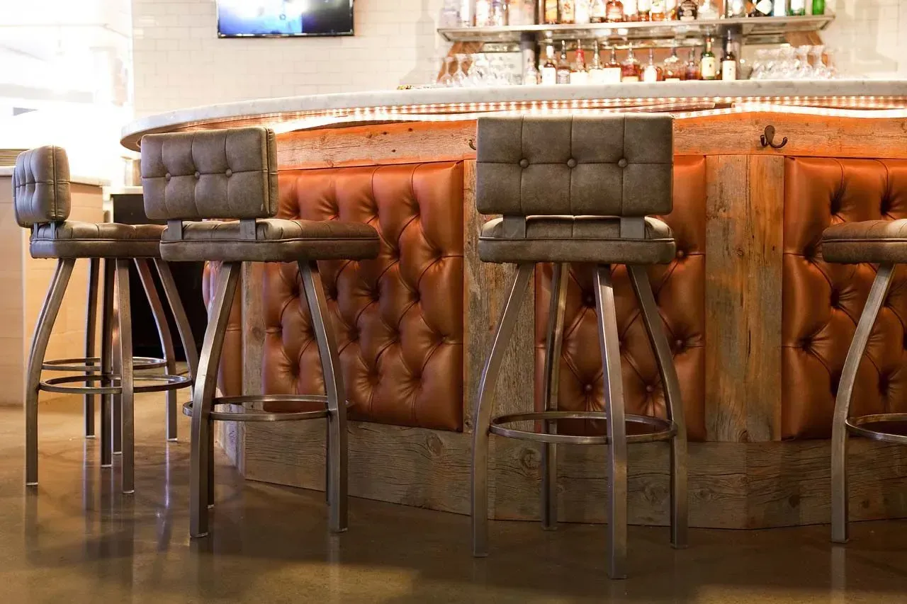 Three bar stools are sitting in front of a bar in a restaurant.