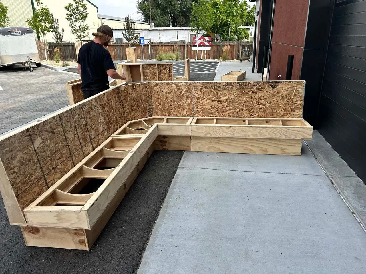 A man is working on a wooden bench in a parking lot