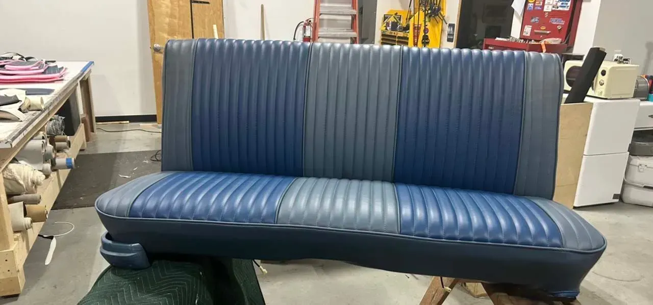 A blue and gray couch is sitting in a garage.