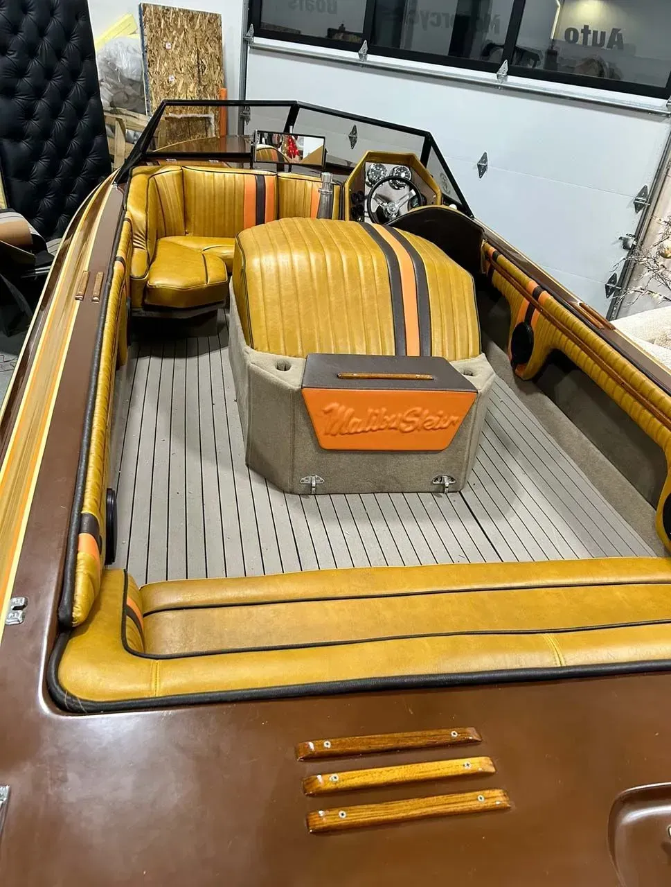 A boat with yellow seats and orange stripes is parked in a garage.