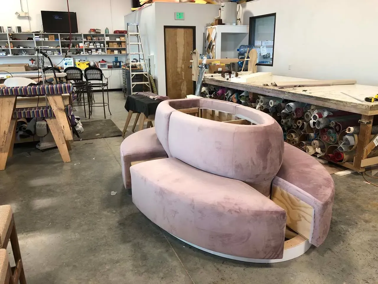 A pink couch is being built in a workshop.