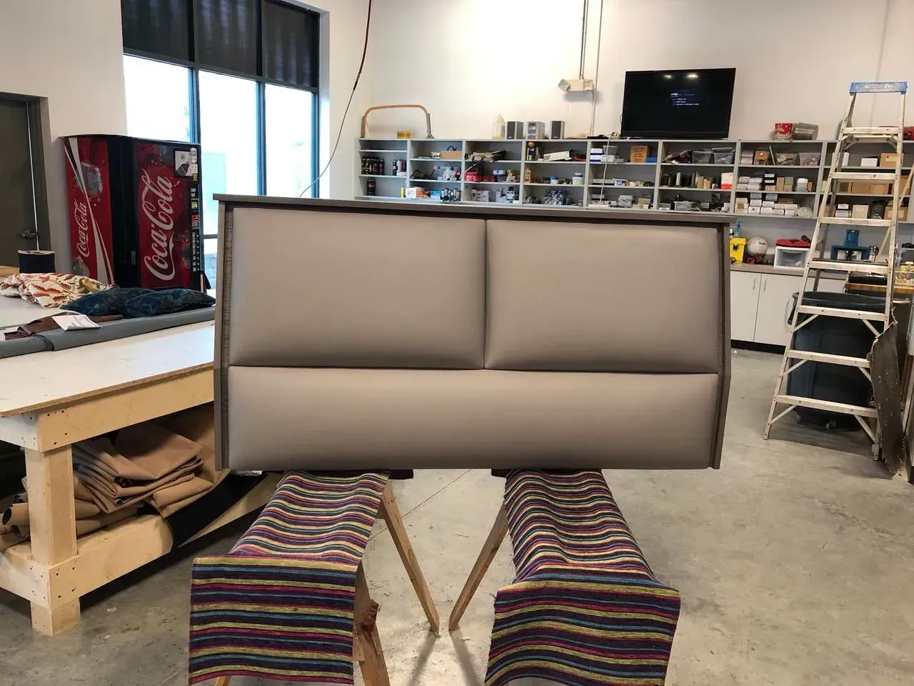 A couch is sitting in a room with a coca cola machine in the background.